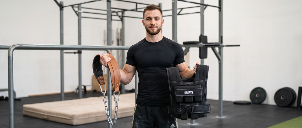 A man holding a weighted vest and dip belt