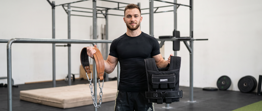 A man holding a weighted vest and dip belt